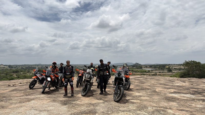 Riders and adventure motorcycles on a rocky plateau under a wide sky
