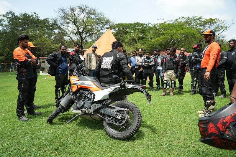 A rider demonstrating bike control to a group gathered round at a skills session
