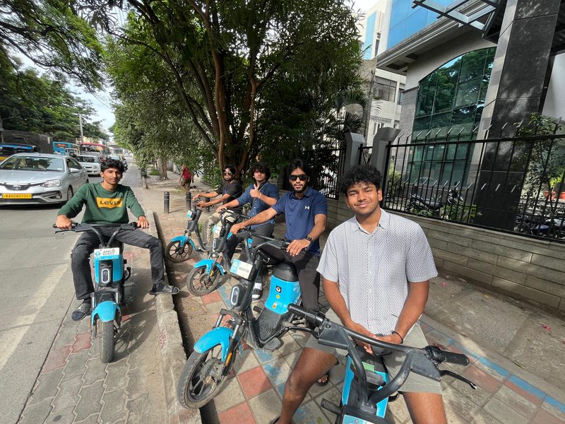 Friends out on rented e-bikes, stopped along a tree-lined city street