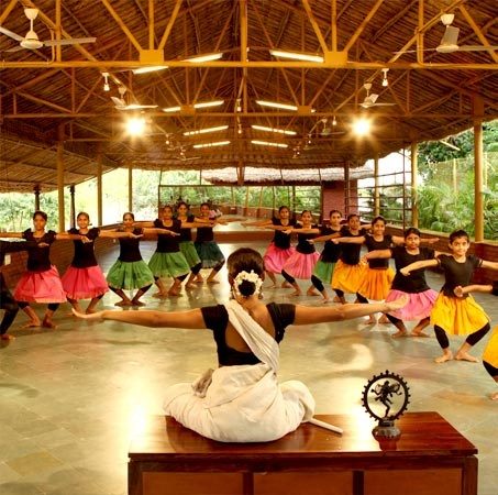 A dance teacher leading a class of students through a pose in an open hall