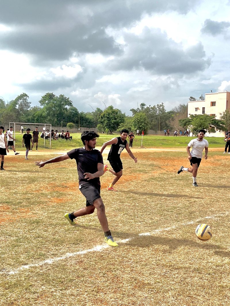 A player striking the ball during a football match on a neighbourhood ground