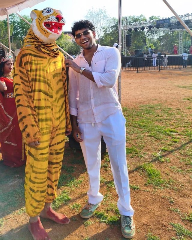 Ambarish Iyengar, founder and CEO of Ilaka, grinning next to someone in a tiger costume at a local festival