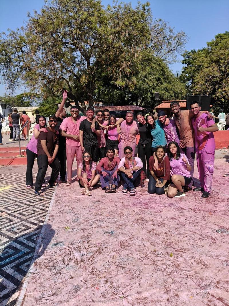 A group covered head to toe in pink colour posing together at a Holi celebration